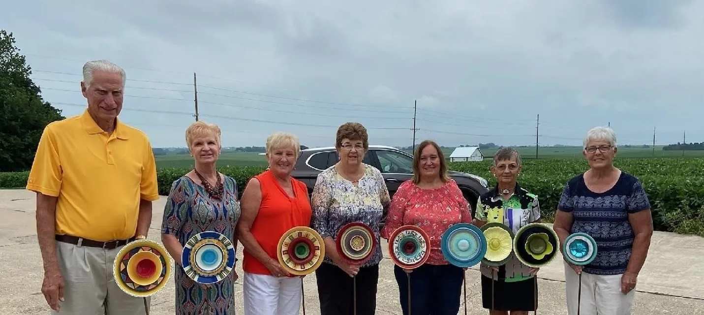 Seven church members displaying colorful garden crafts outside